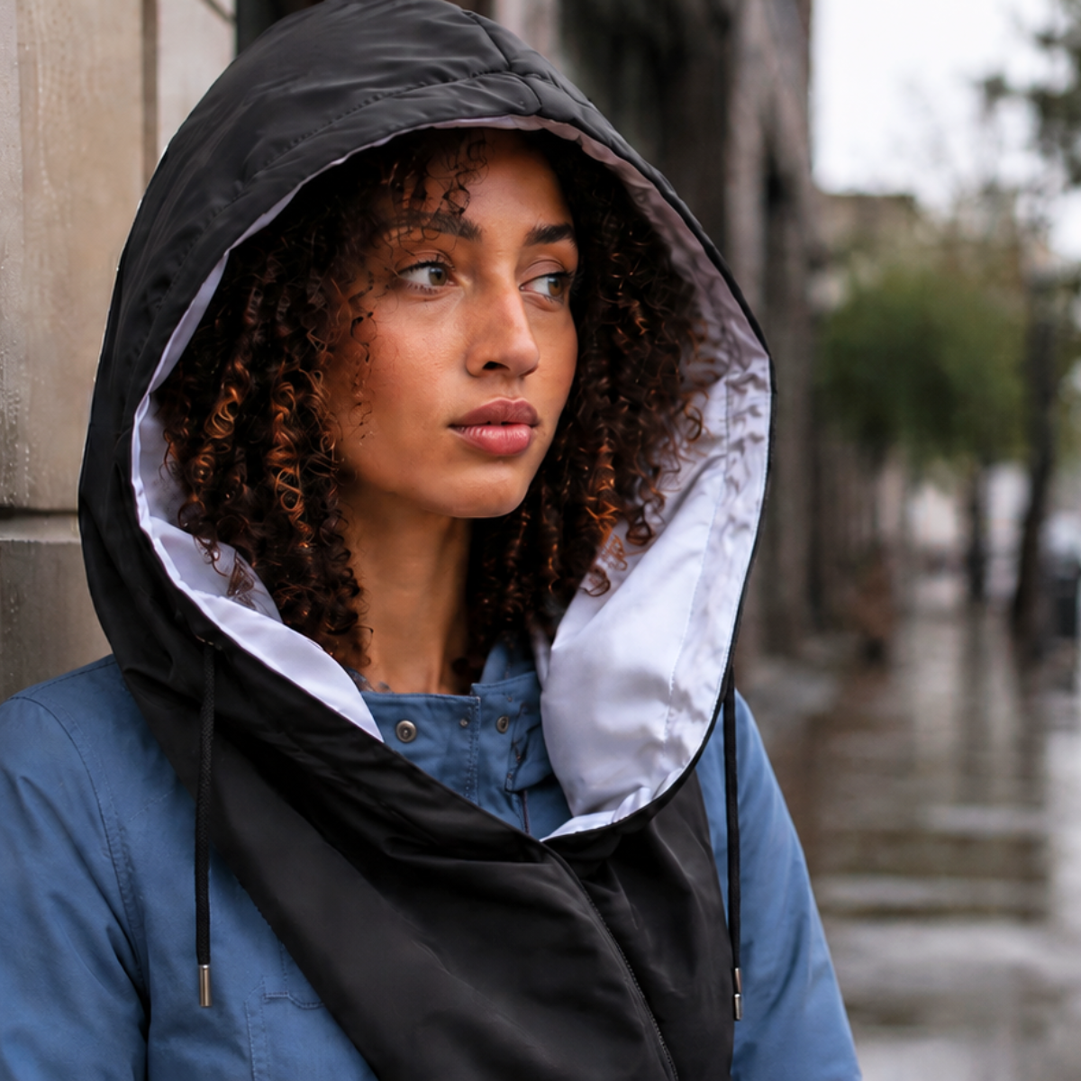 Woman with natural curly hair wearing a roomy hooded scarf for rain coverage