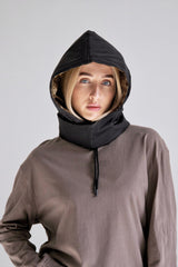 Person wearing a brown hoodie with a black hood against a plain background