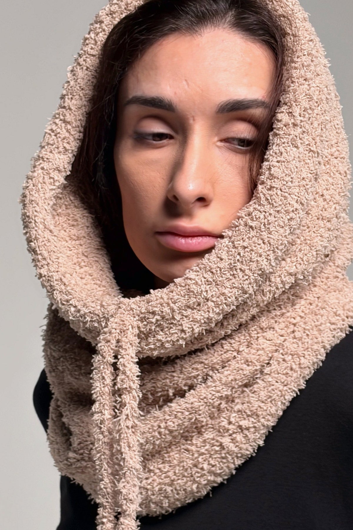 Beige knit cowl scarf styled around the neck with a soft relaxed drape